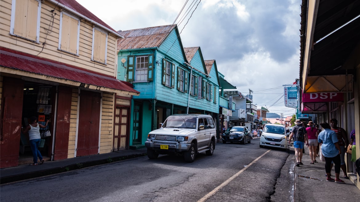 A street in the downtown area of St John's in Antigua and Barbuda, with cars, pedestrians and colorful buildings.