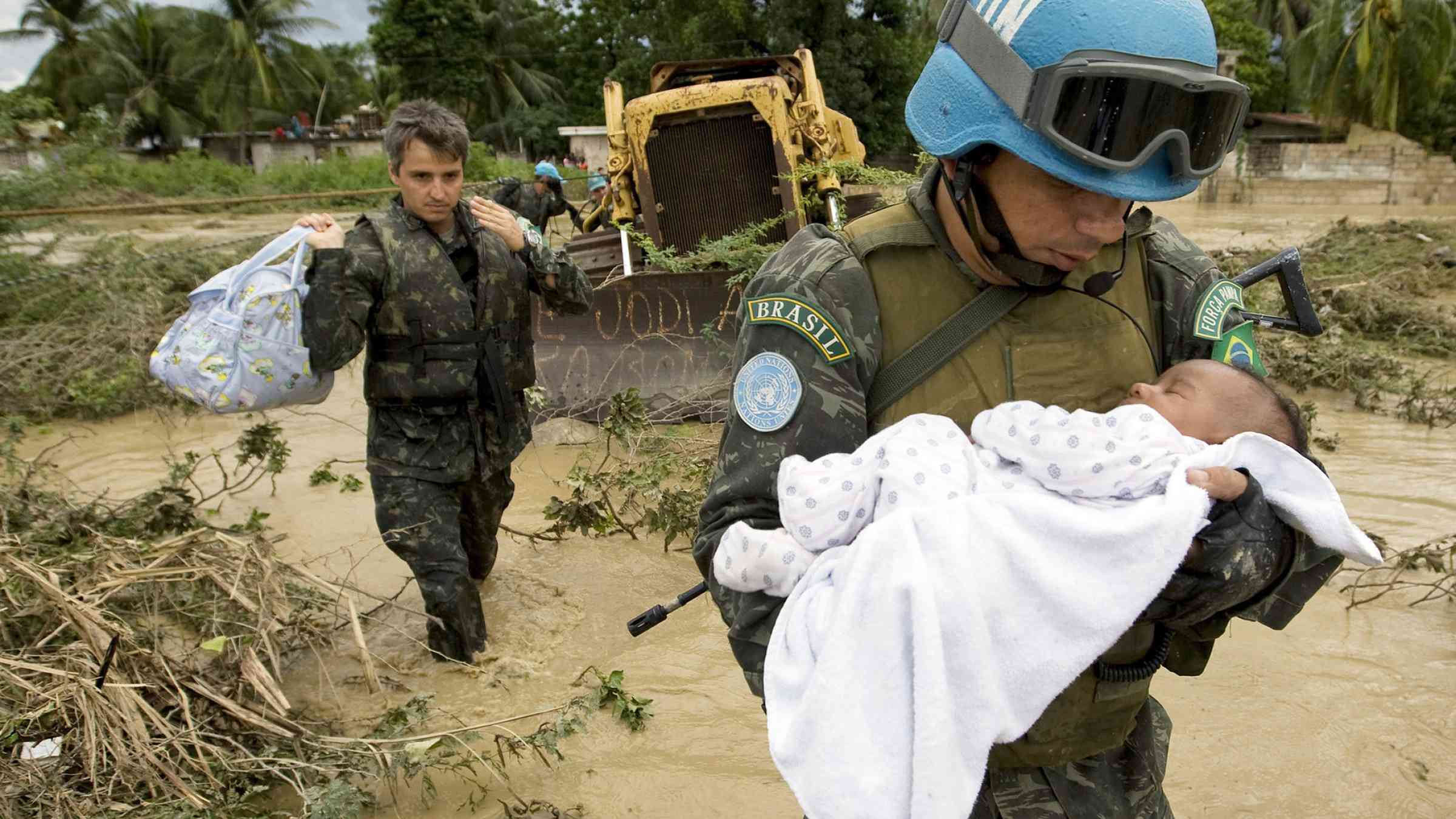 UN peacekeeper carrying a infant whose family was impacted by flooding in Haiti in 2007