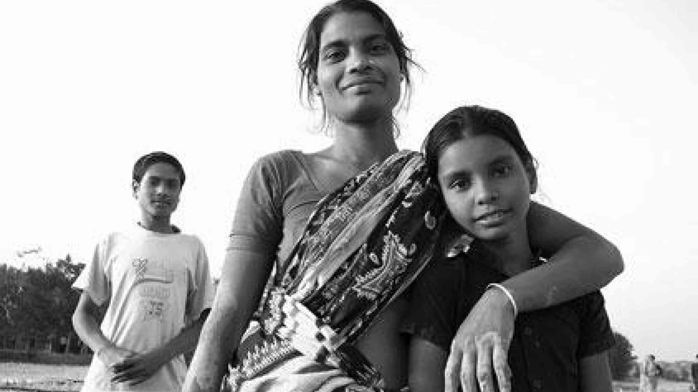 A woman protects her family, her sand-covered hands evidence of the hard-labour she is performing to restore her dwelling, after the devestation of Cyclone Sidr in 2007. (Photo/Belinda Meggitt & Mickey Leung)